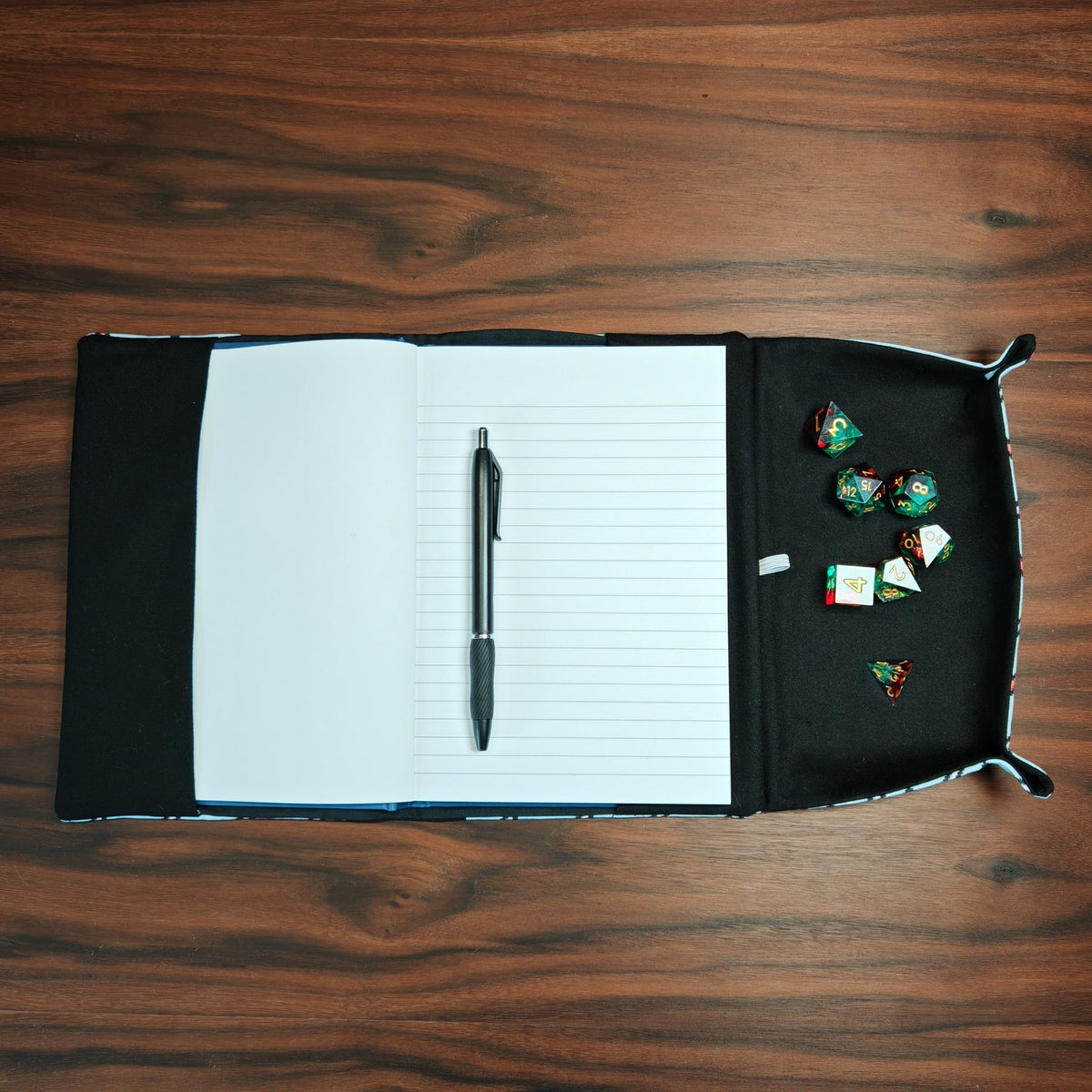 Top-down gaming notebook showing dice in built-in dice tray